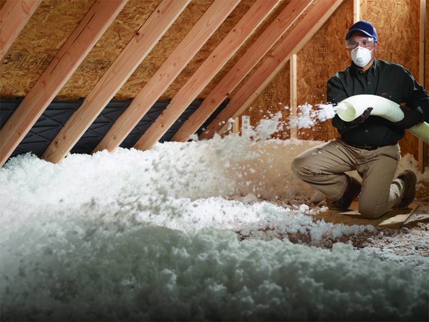 Installer blowing insulation into an attic
